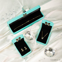Idol Beauty Elegantes joyas presentadas en cajas de terciopelo turquesa, que incluyen una pulsera, aretes y un collar, rodeados de diamantes falsos.