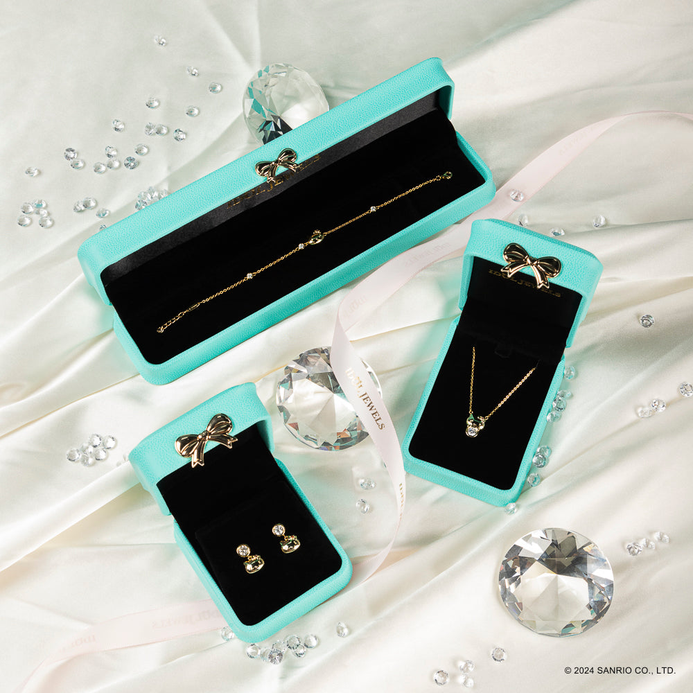 Elegantes joyas presentadas en cajas de terciopelo turquesa, que incluyen una pulsera, aretes y un collar, rodeados de diamantes falsos.